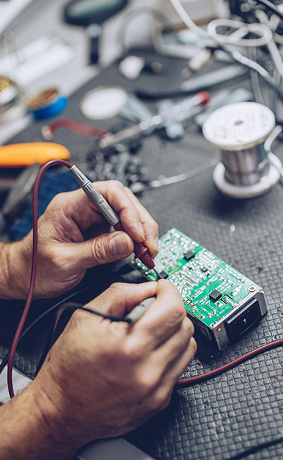 Mérnök vagy szerelő, aki forrasztópákával elektronikus áramköri lapot javít.