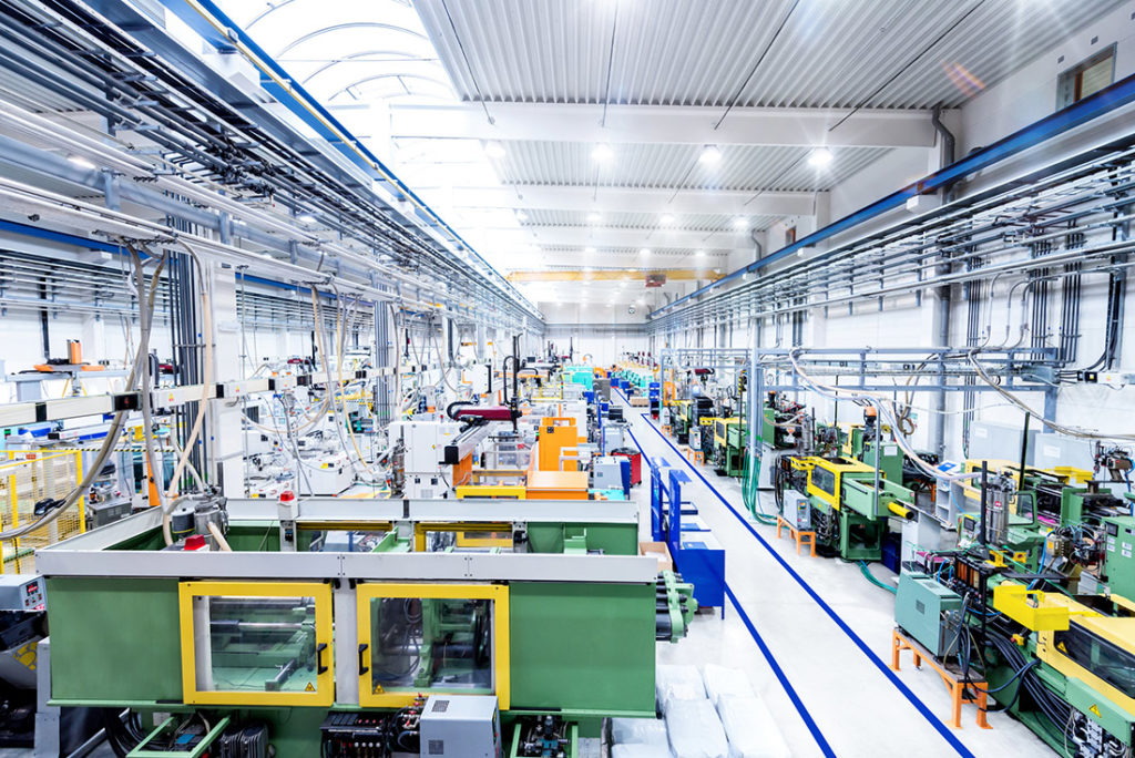 Una fabbrica futuristica è raffigurata in una grafica a colori orizzontale. I macchinari moderni con le braccia robotiche occupate circondano un corridoio industriale.