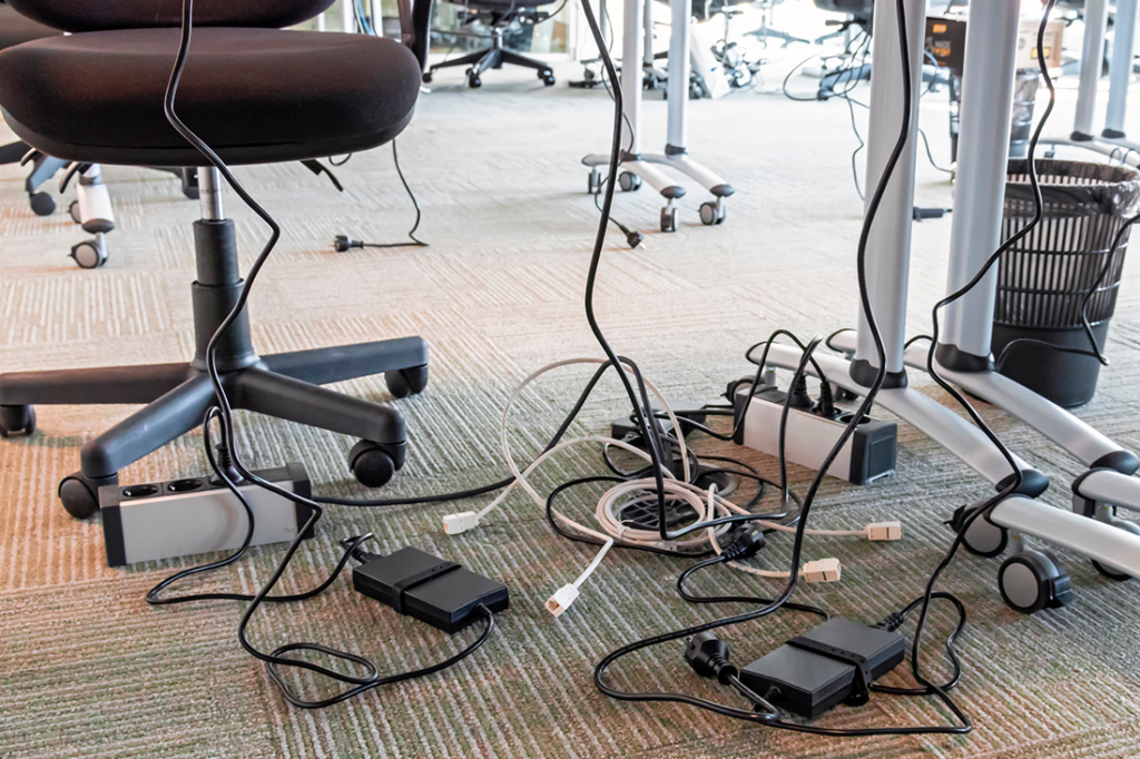 Office clutter concept. Unwound and tangled electrical wires under the table. 
